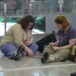 공항<b>구석</b>에서 여성 외국인 두명이 바닥에 앉아 뭔가 하고 있었다.